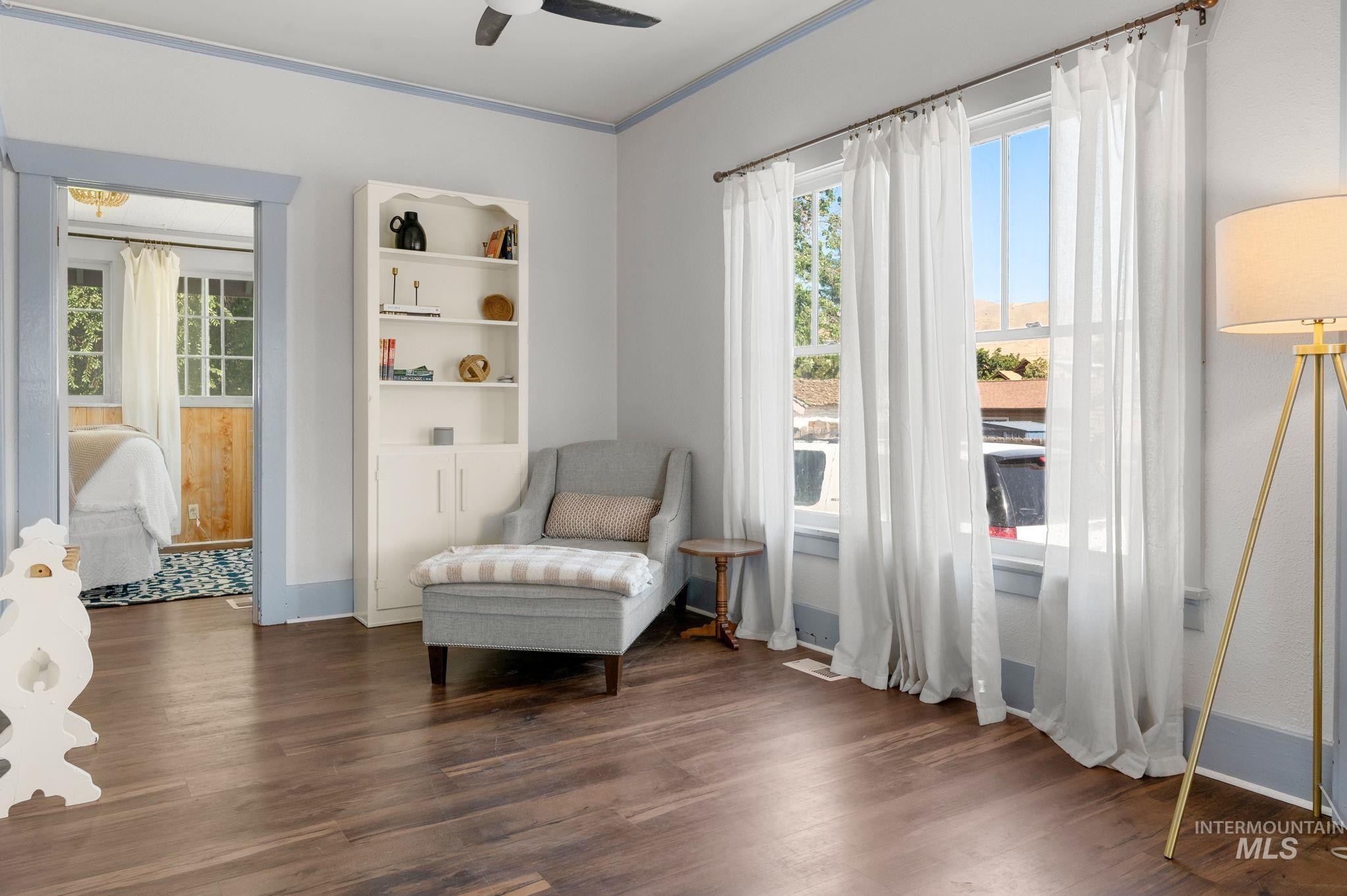 Sitting room featuring dark wood-type flooring, a ceiling fan, and ornamental molding
