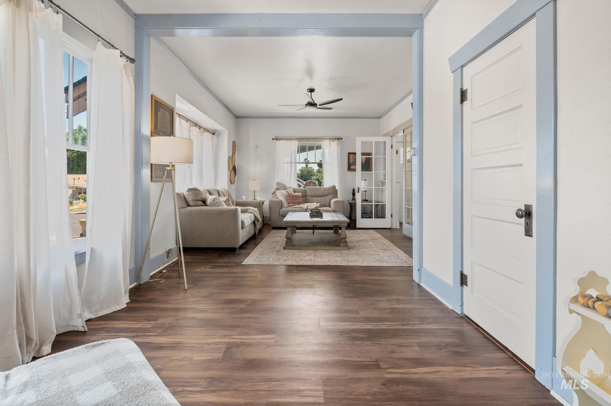Living area with french doors, a ceiling fan, and dark wood-style flooring