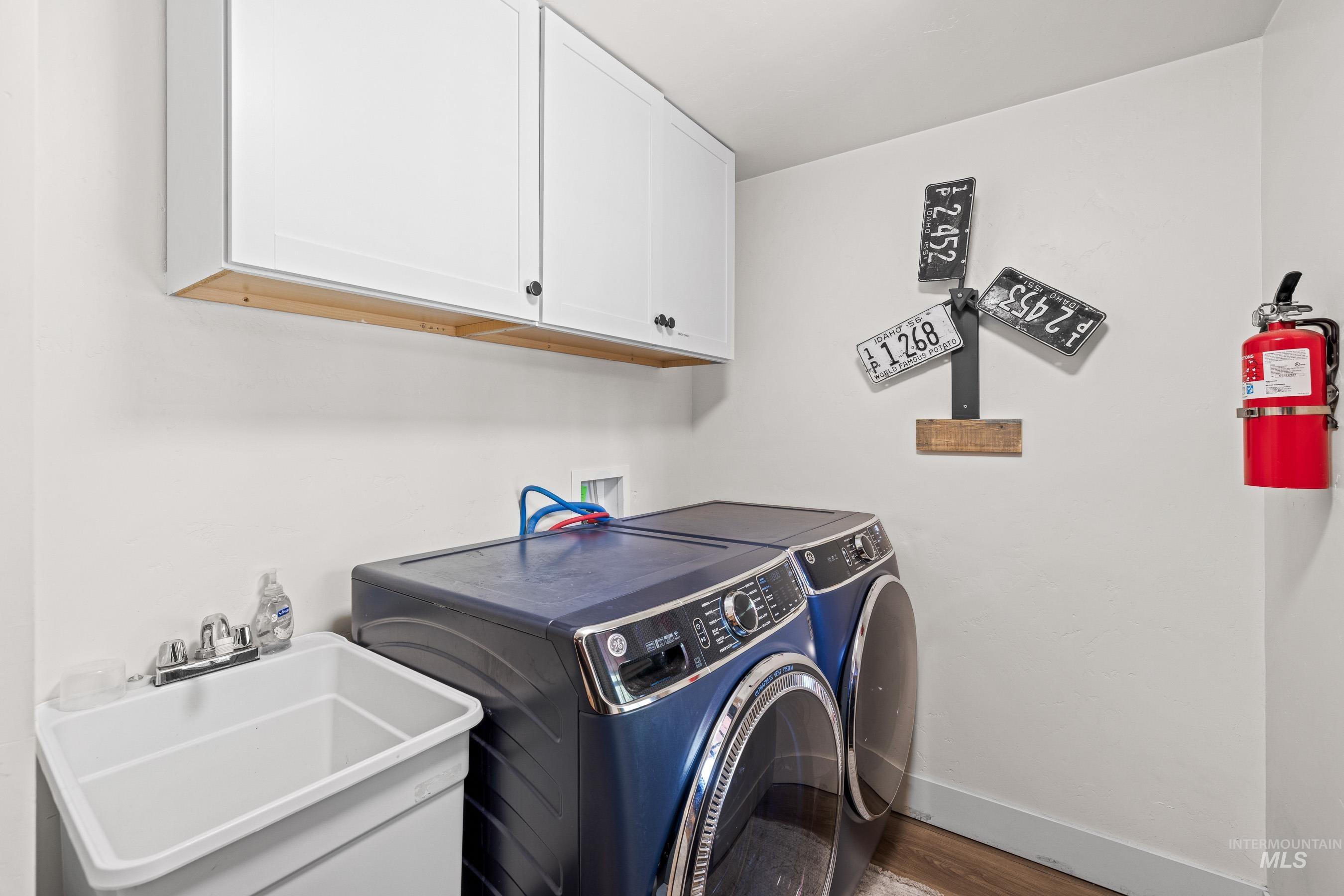 Laundry area with independent washer and dryer, cabinet space, and wood finished floors