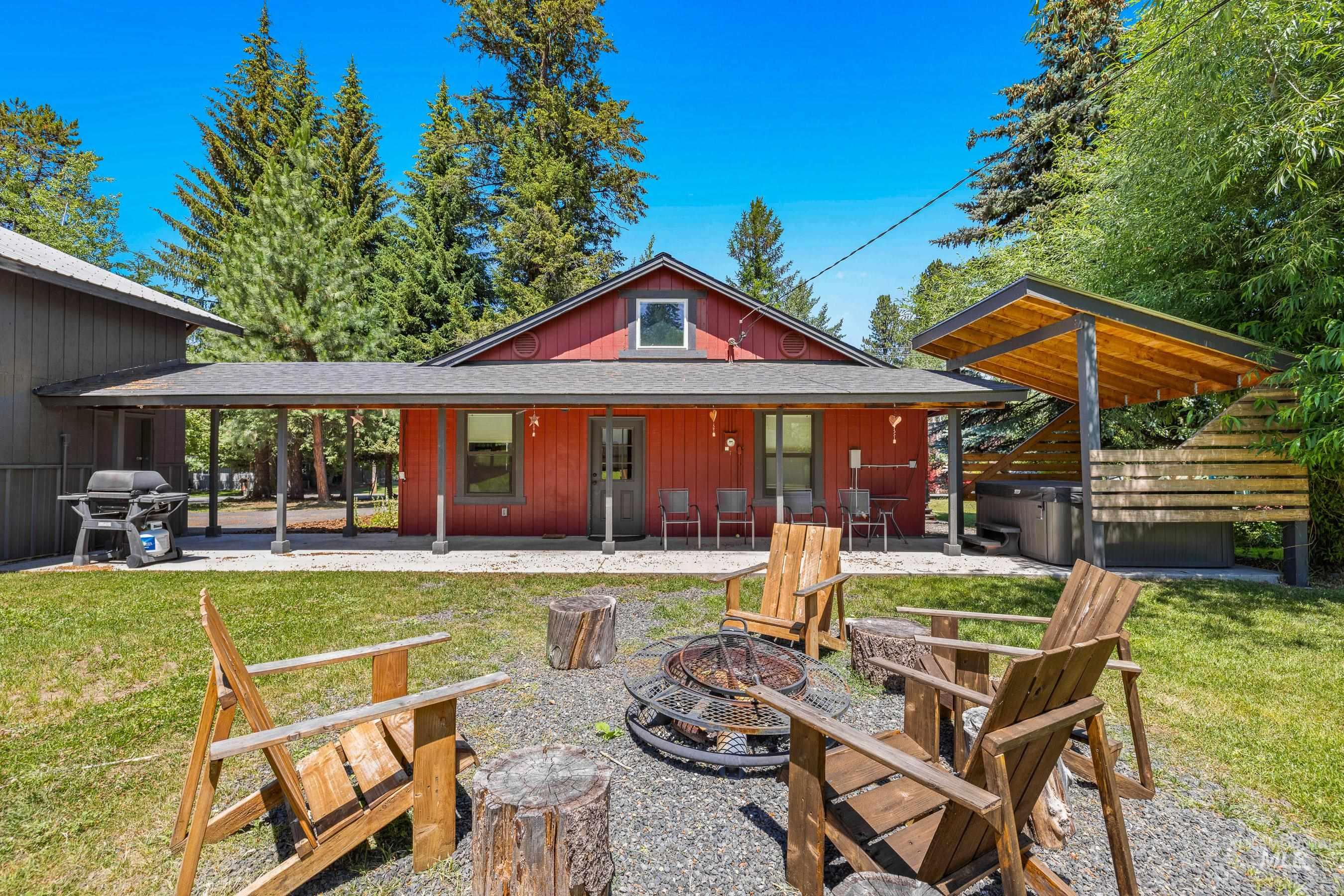 Back of property with a fire pit, a patio, a lawn, and roof with shingles