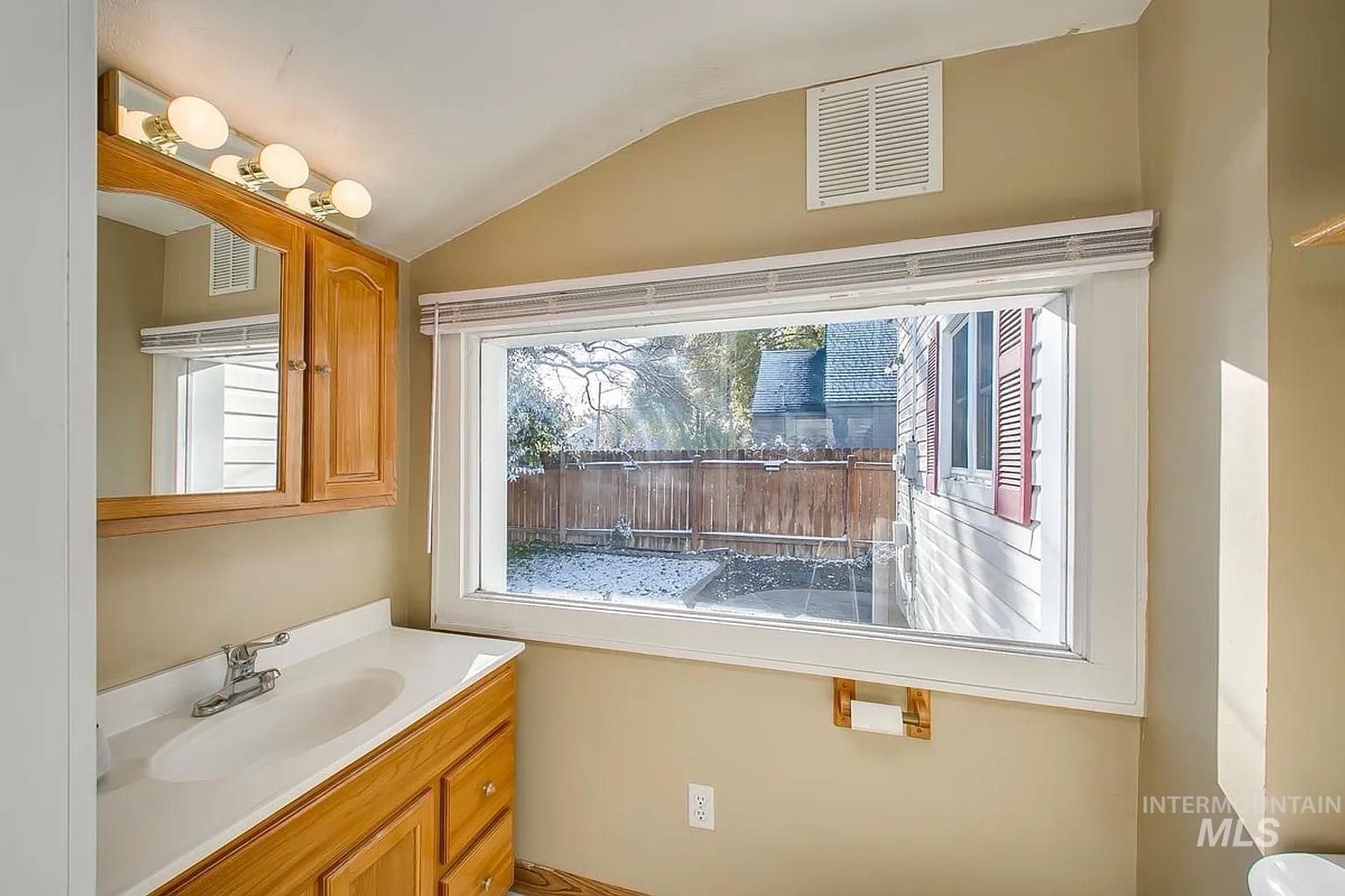 Bathroom featuring vaulted ceiling and vanity