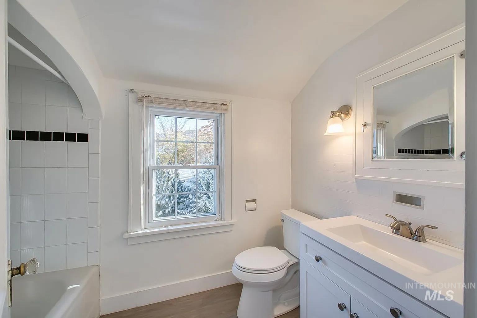 Bathroom with vanity, vaulted ceiling, and wood finished floors