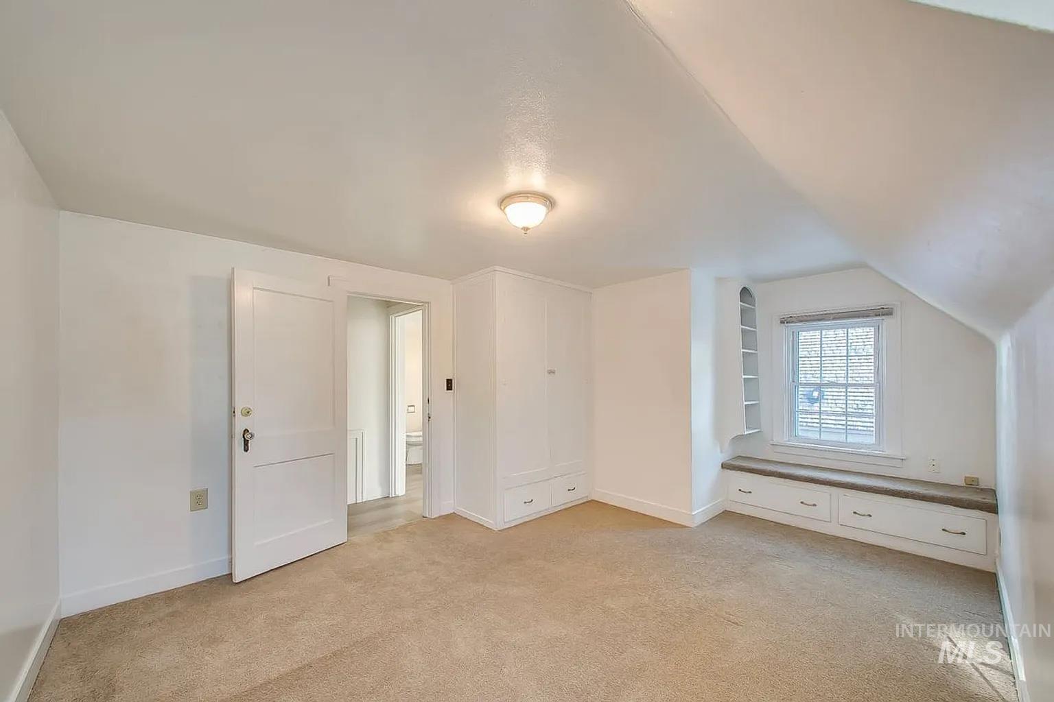 Additional living space featuring light colored carpet and lofted ceiling