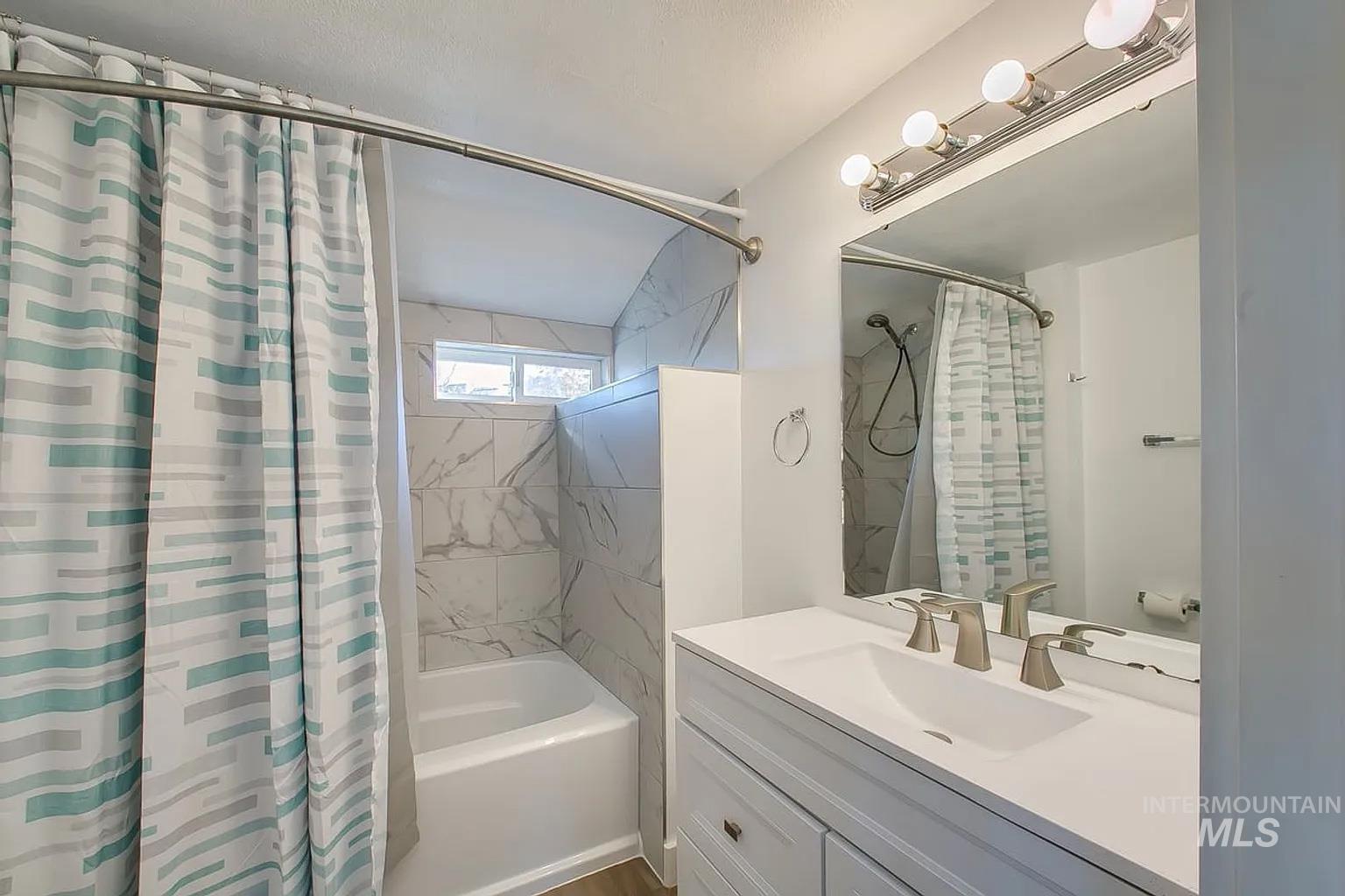 Bathroom with shower / bath combo with shower curtain and vanity