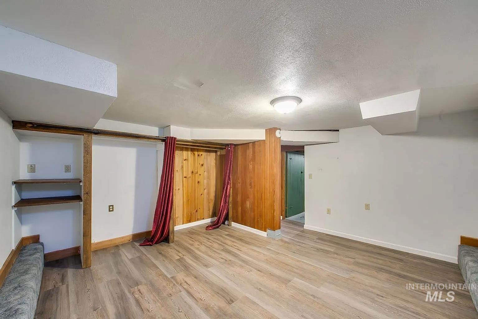 Finished basement with a textured ceiling and light wood finished floors