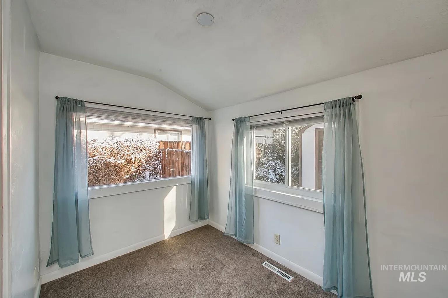 Empty room with vaulted ceiling and carpet
