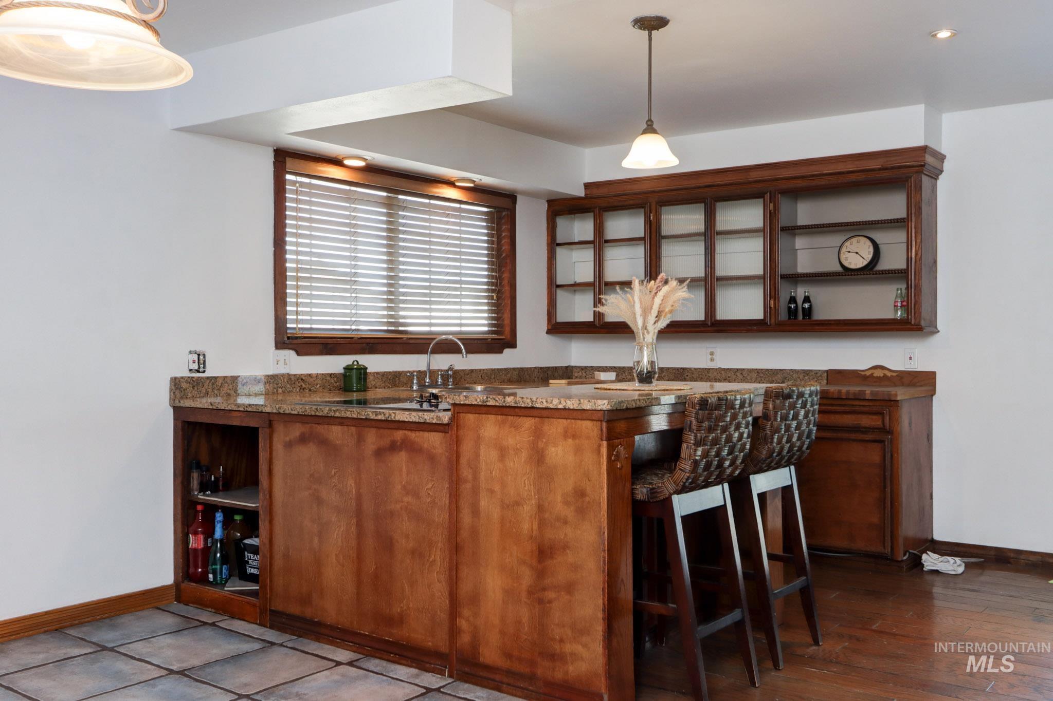 Kitchen featuring open shelves, glass insert cabinets, dark countertops, and pendant lighting