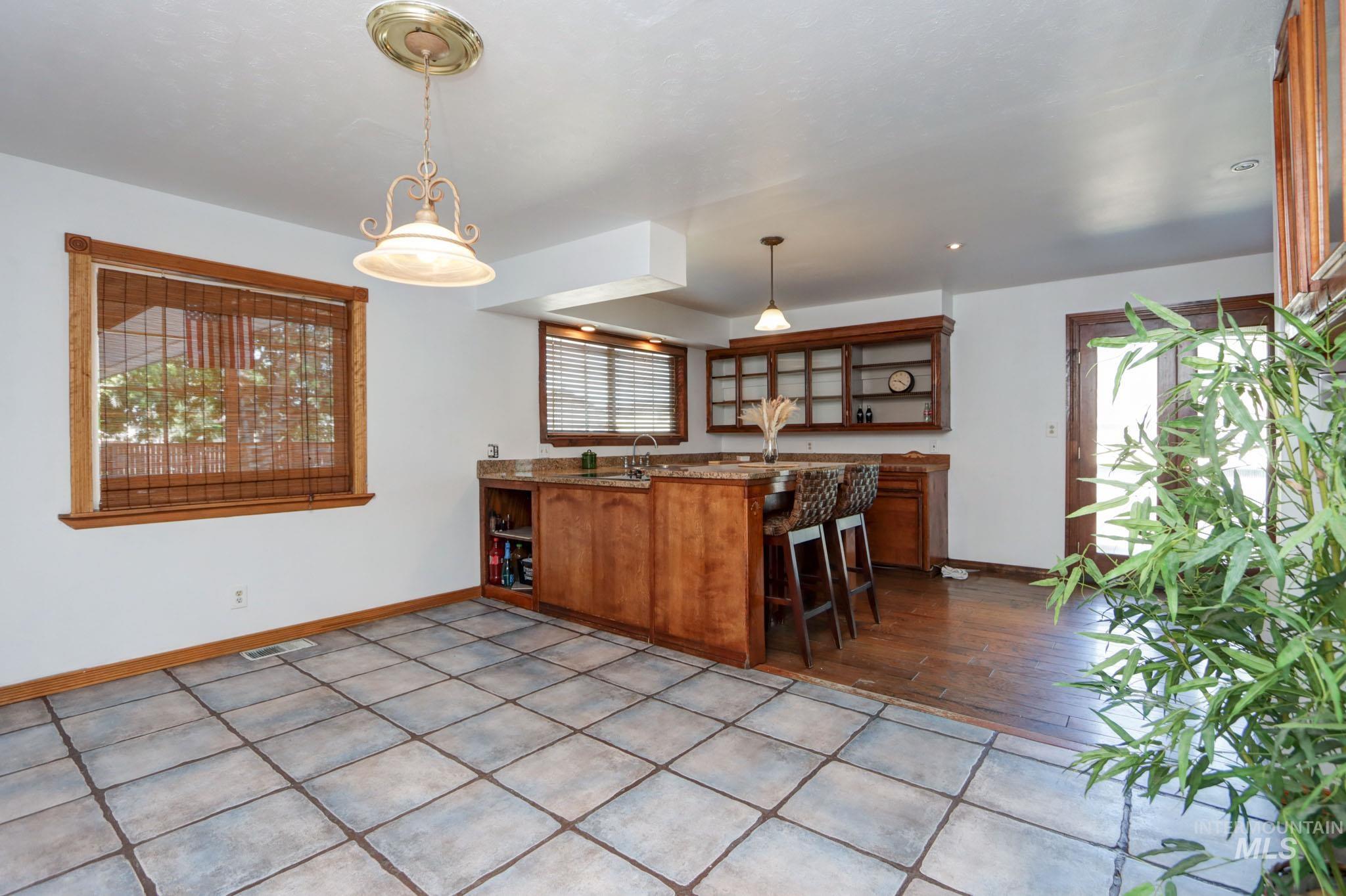 Kitchen featuring open shelves, brown cabinetry, pendant lighting, and a peninsula