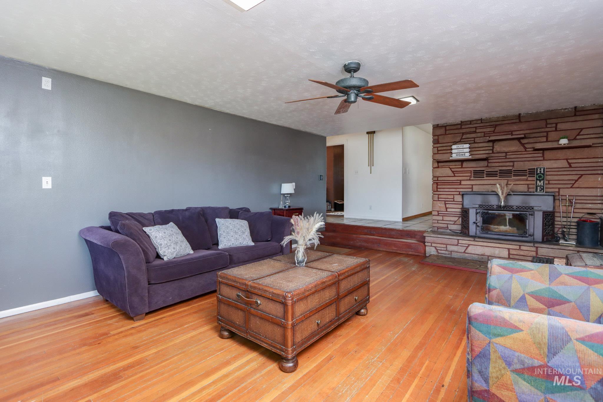 Living area with hardwood / wood-style flooring, a ceiling fan, and a textured ceiling