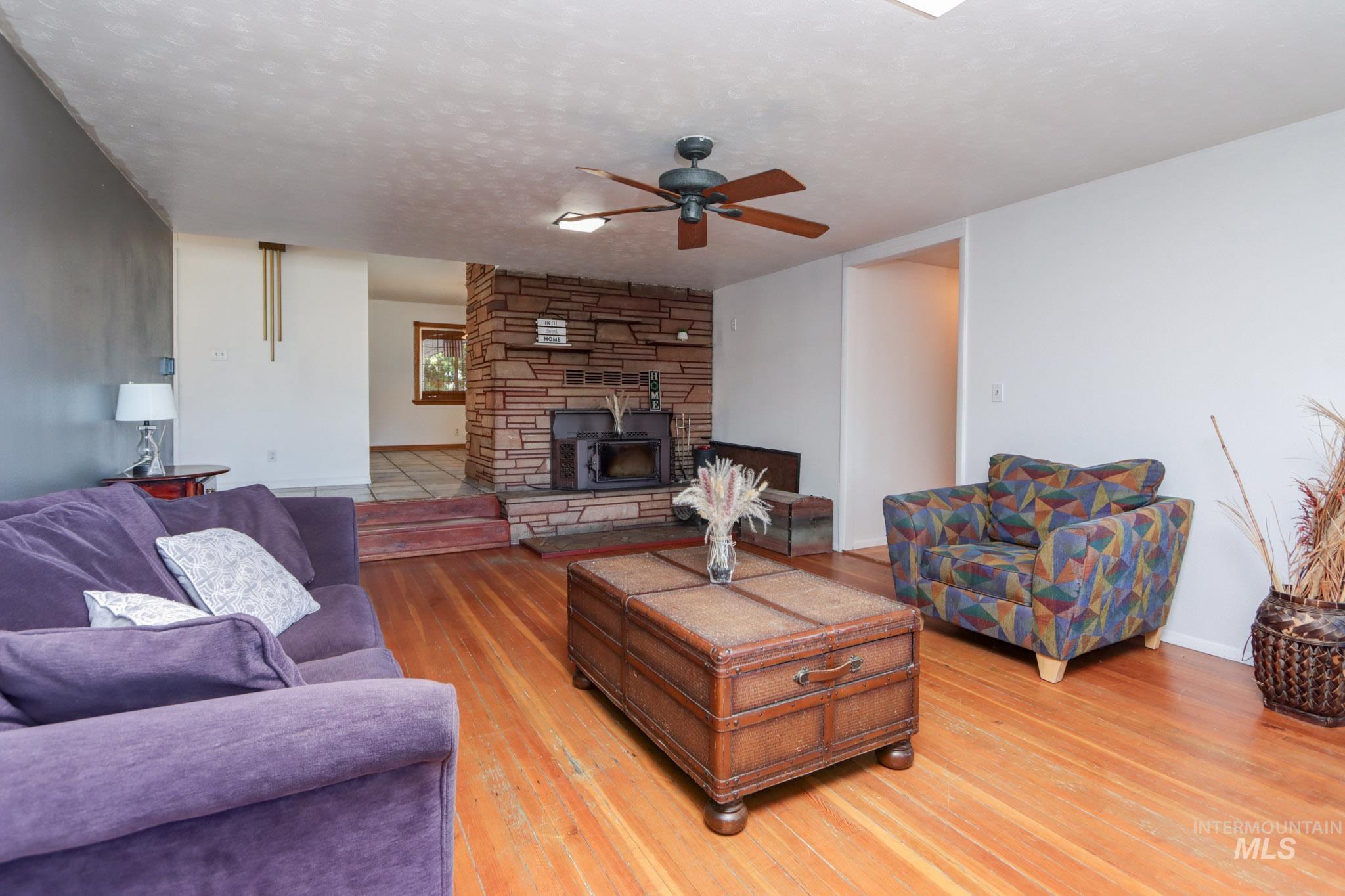 Living room featuring ceiling fan, light wood finished floors, and a textured ceiling