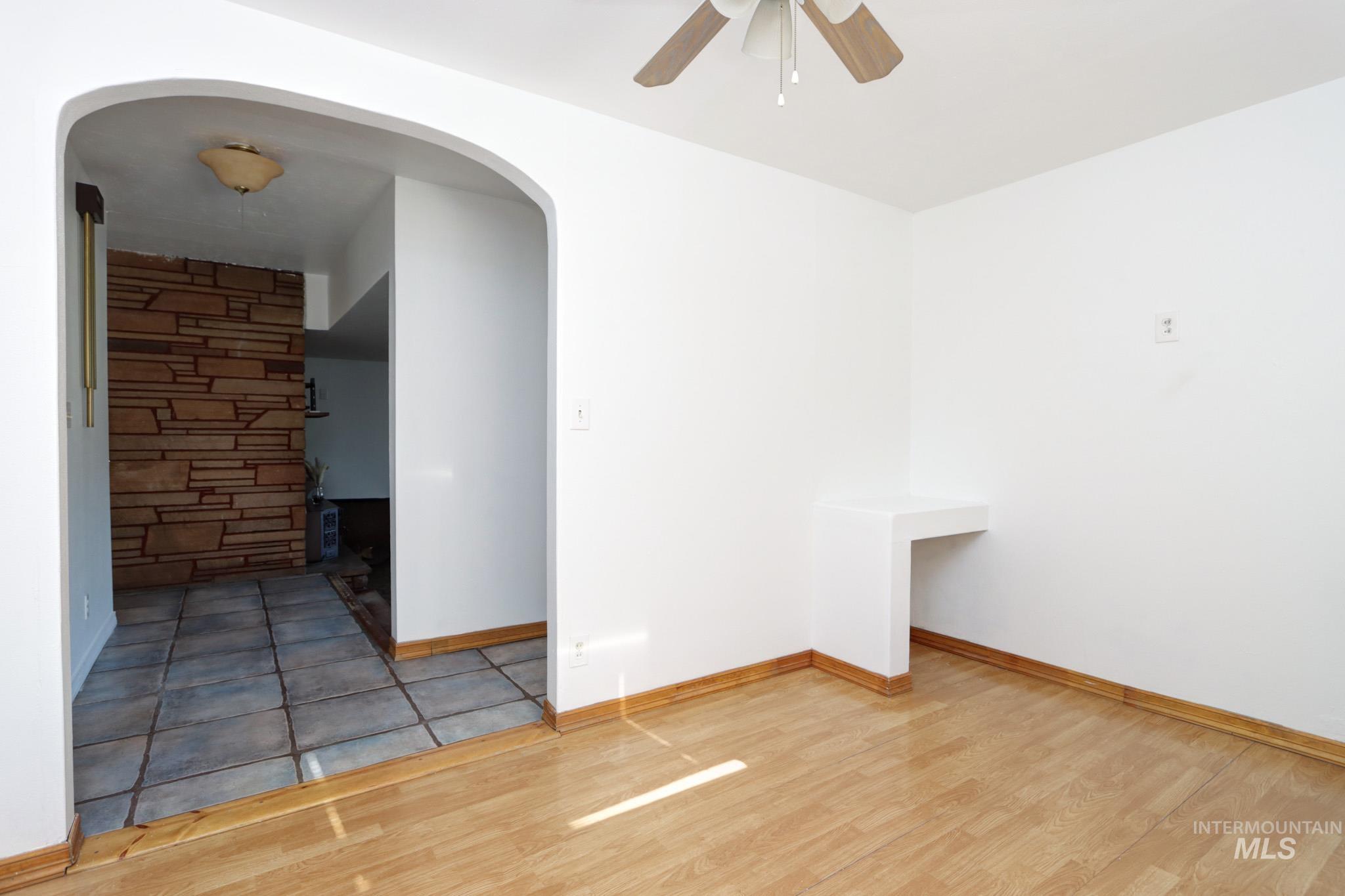Empty room featuring arched walkways, wood finished floors, and ceiling fan