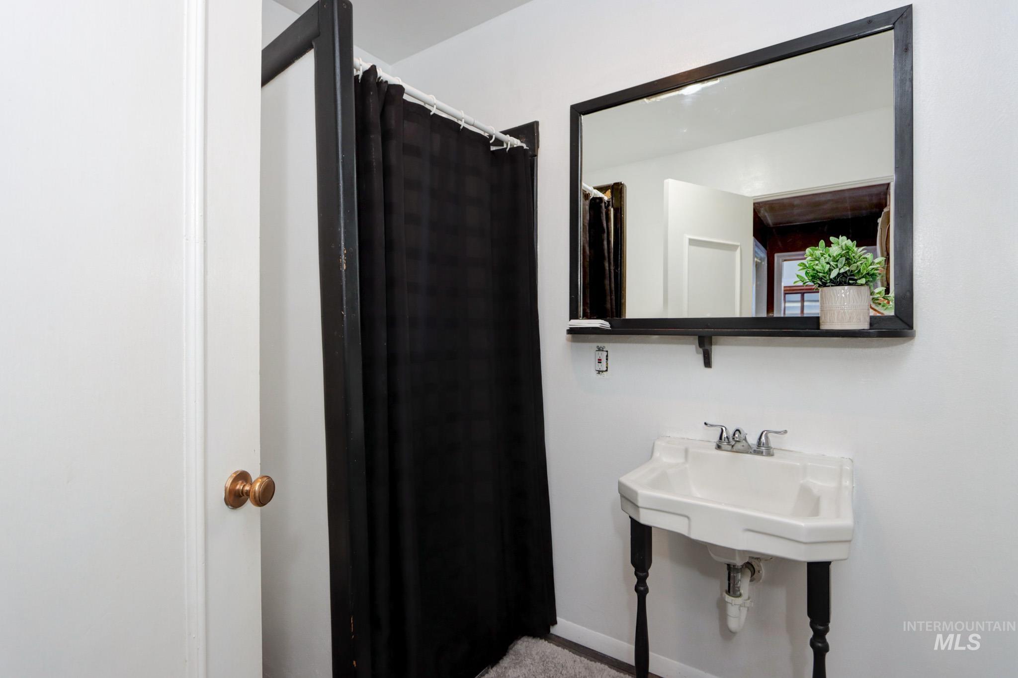 Full bathroom with curtained shower and baseboards