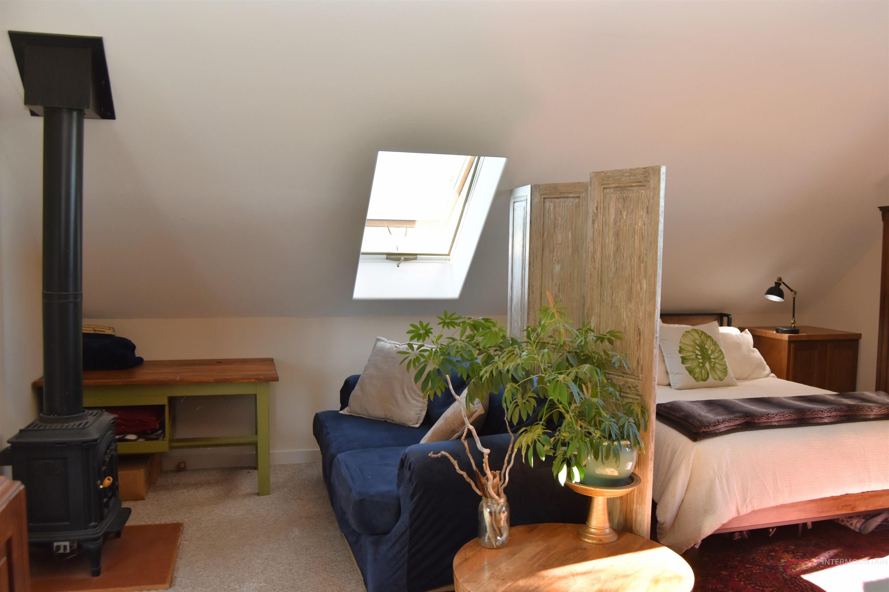 Bedroom featuring a skylight, carpet floors, and a wood stove