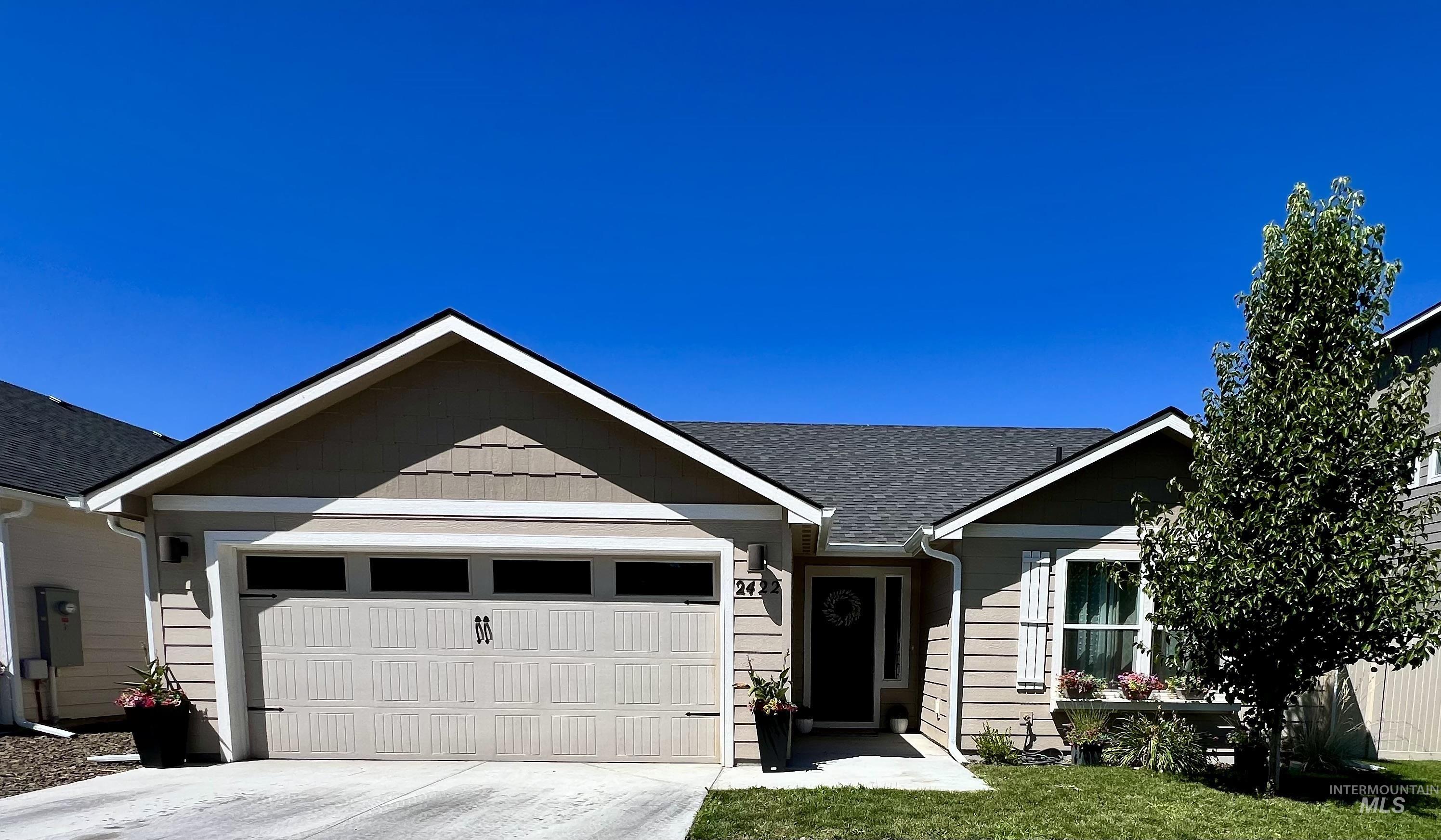 Single story home with an attached garage, concrete driveway, and a shingled roof