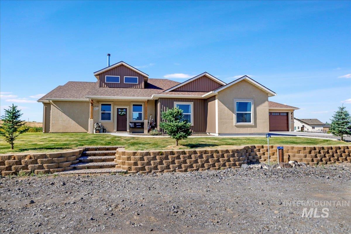 View of front facade with board and batten siding, driveway, an attached garage, and a front lawn