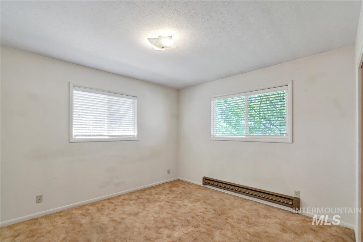 Unfurnished room featuring baseboard heating and carpet flooring