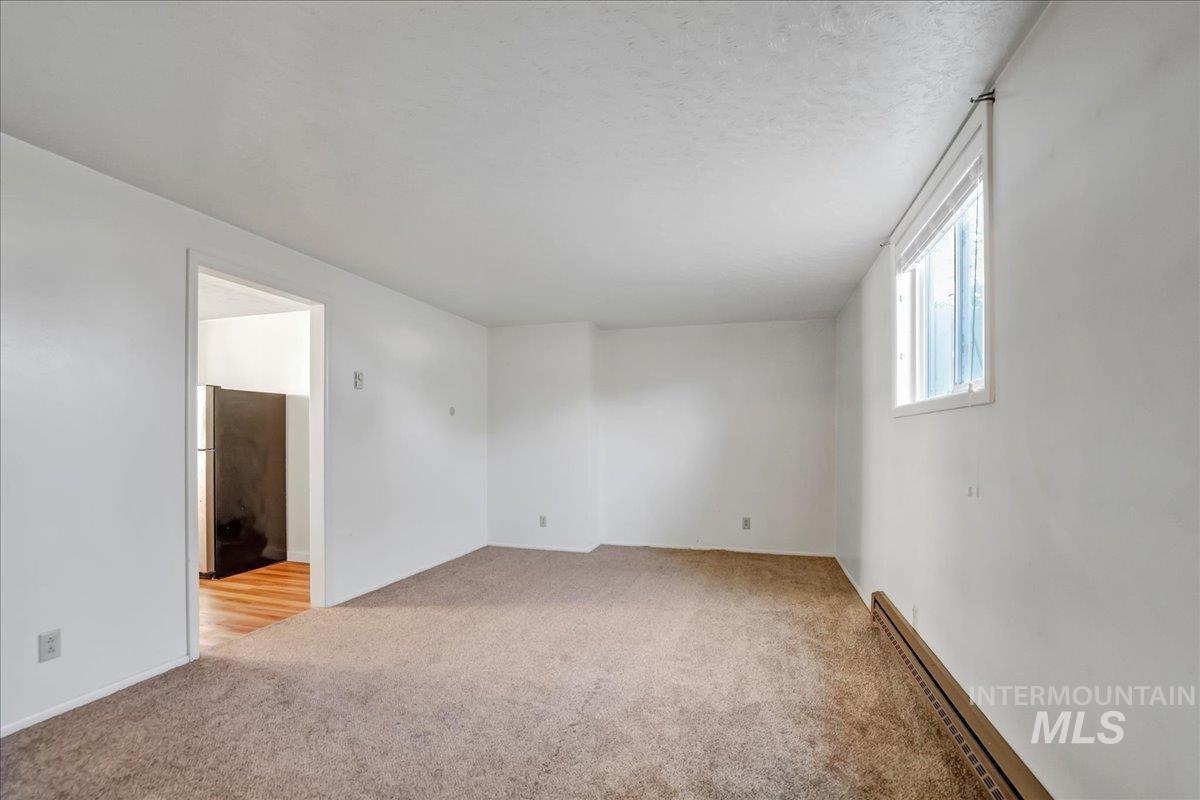 Unfurnished room with light colored carpet and baseboard heating