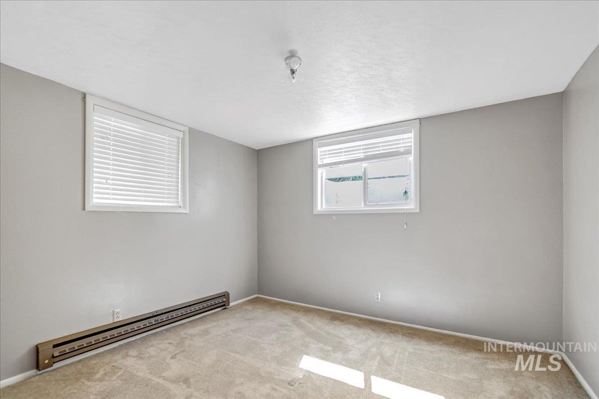 Unfurnished room featuring baseboard heating and carpet floors