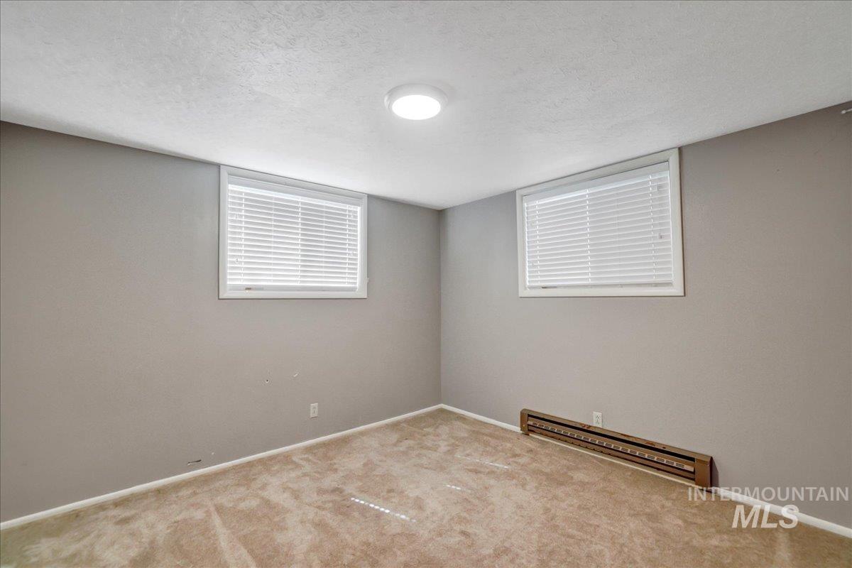 Carpeted empty room with a baseboard heating unit and a textured ceiling