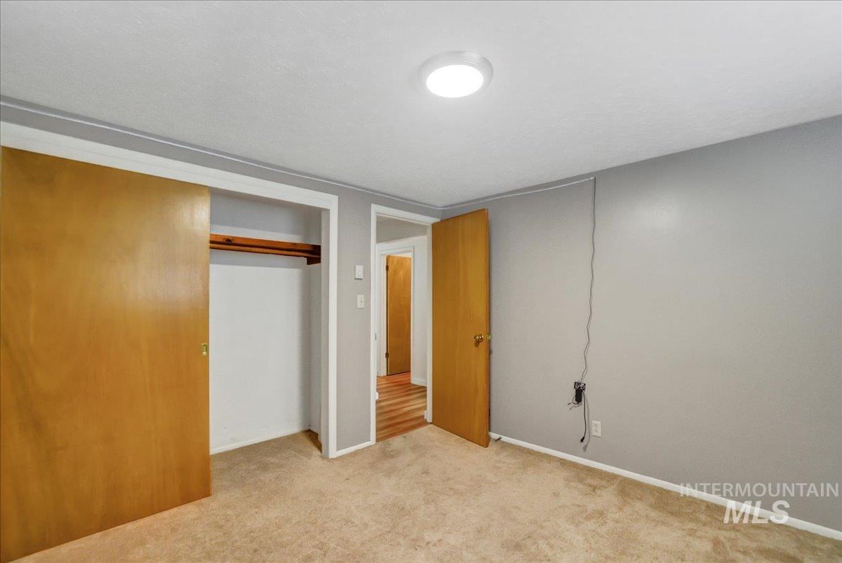 Unfurnished bedroom featuring light carpet and a closet