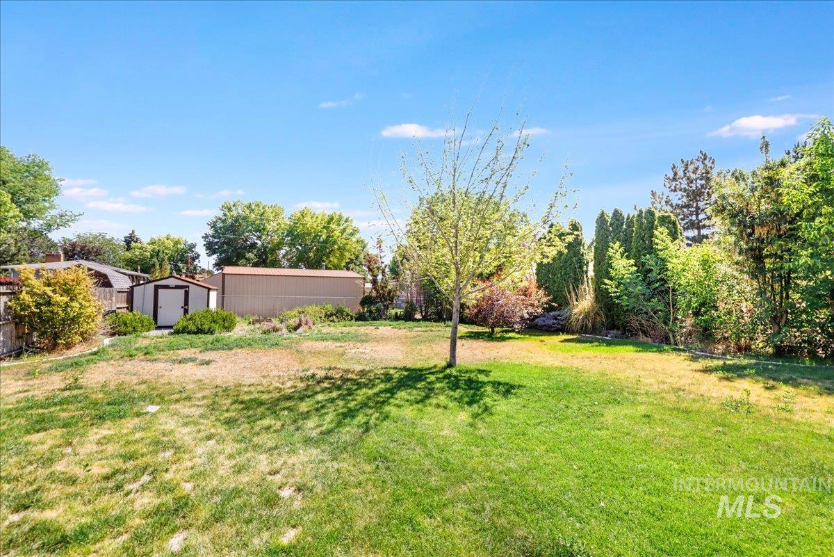 View of green lawn featuring a storage unit