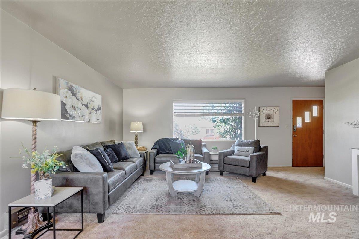 Living area featuring carpet and a textured ceiling