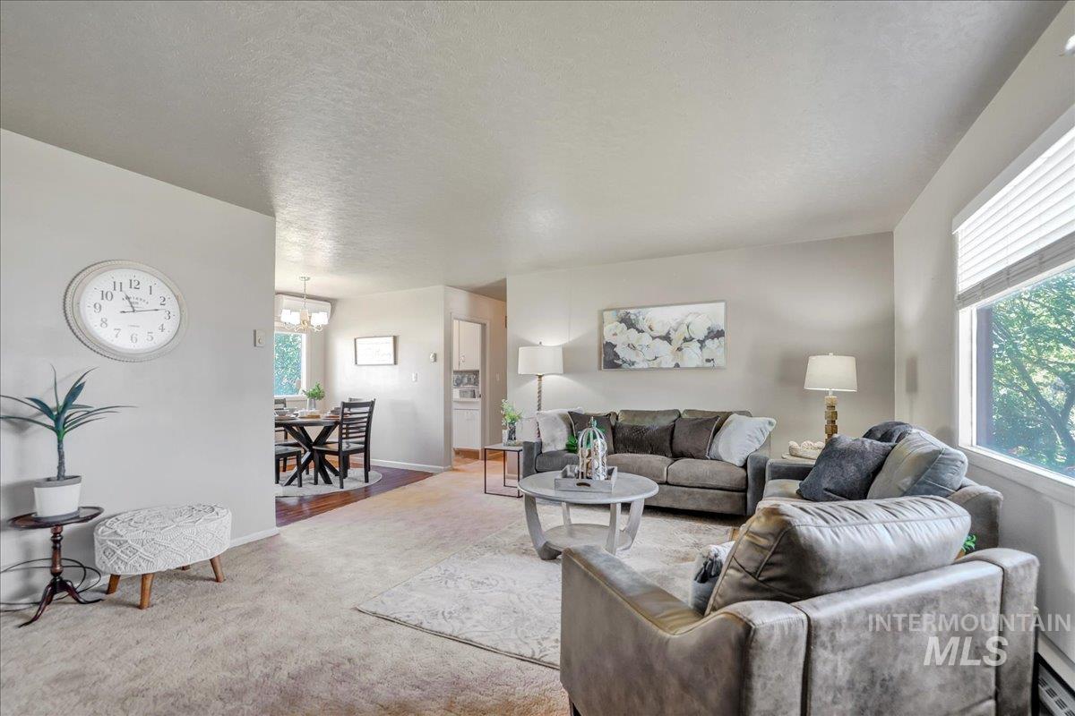 Carpeted living area featuring a chandelier and baseboards