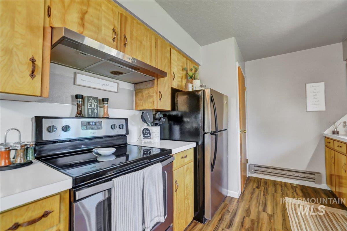 Kitchen with appliances with stainless steel finishes, extractor fan, and light countertops