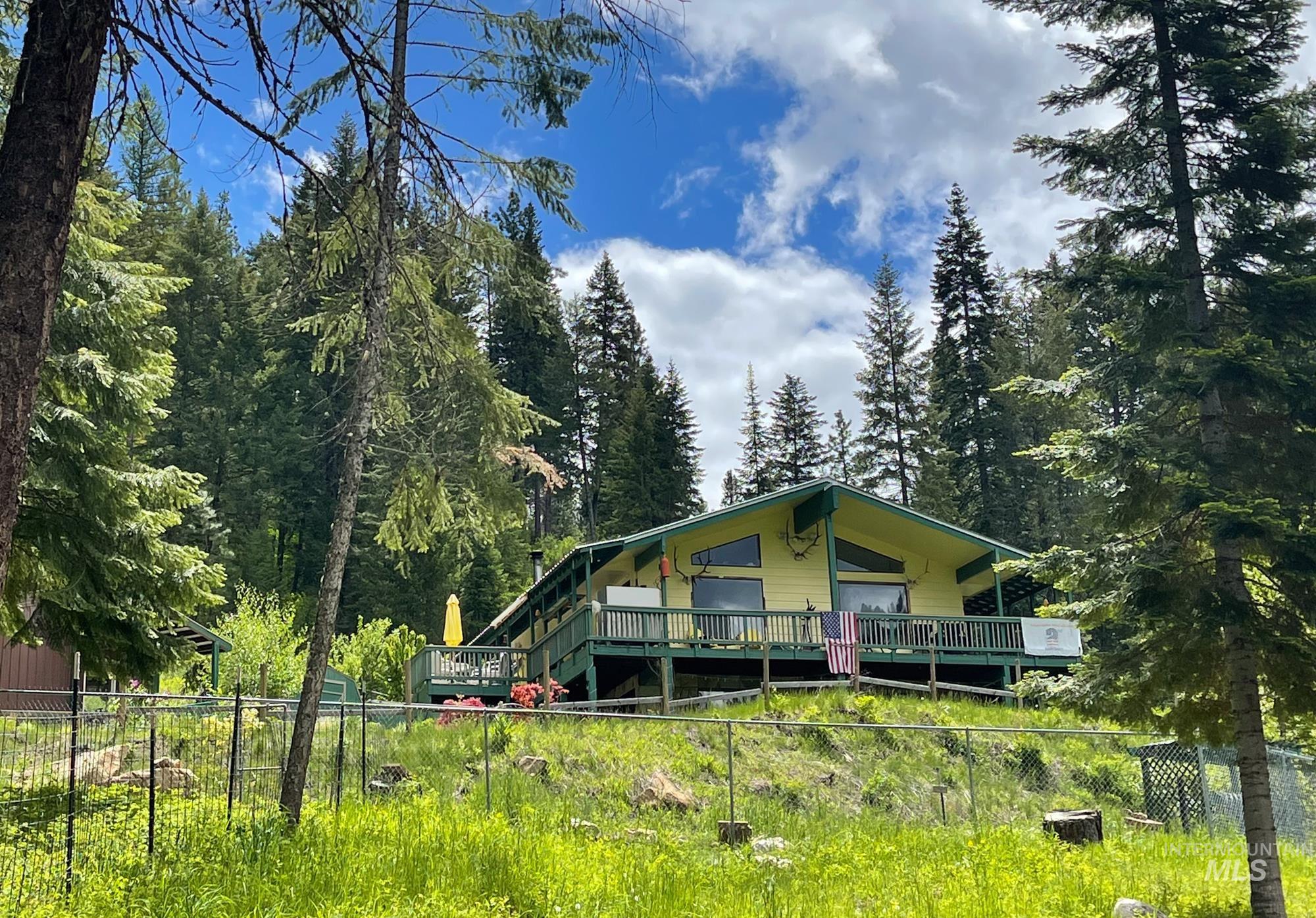 View of front of house with a deck and a wooded view