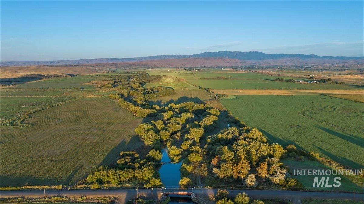Aerial view of property and surrounding area featuring rural landscape and a mountainous background