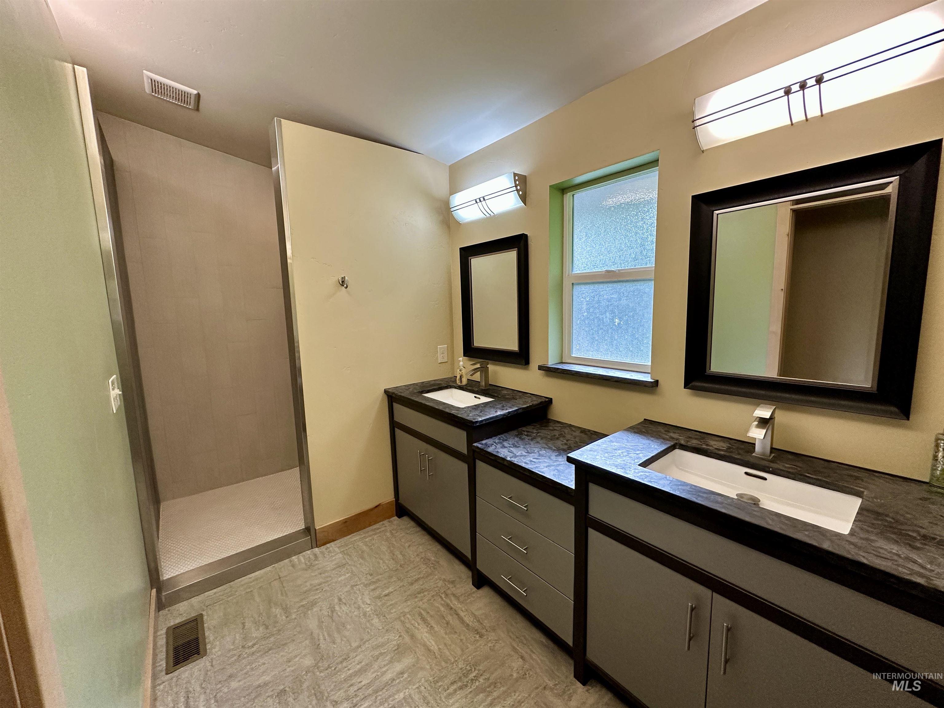 Full bathroom featuring walk in shower and two vanities