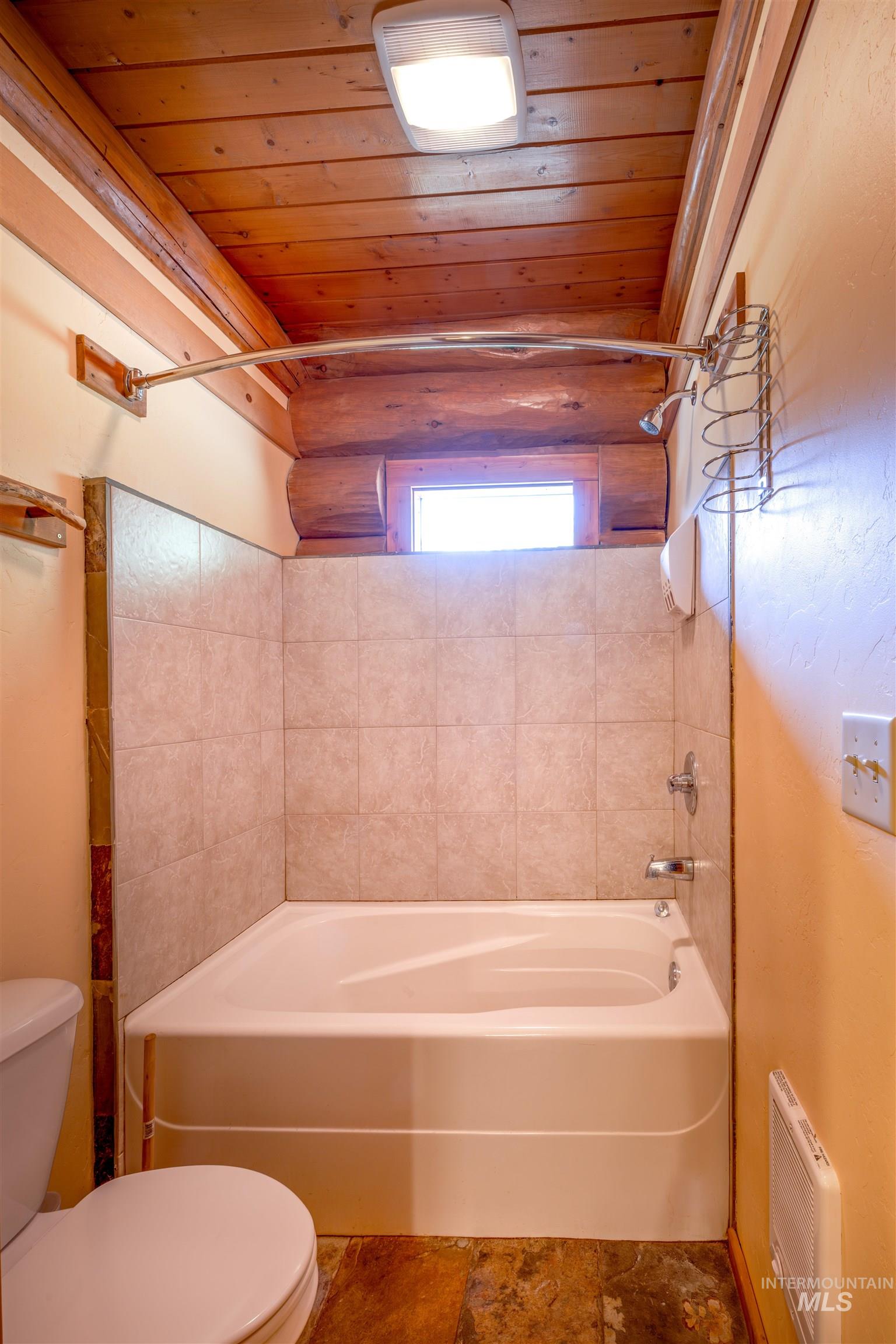 Full bathroom featuring wood ceiling, washtub / shower combination, and heating unit