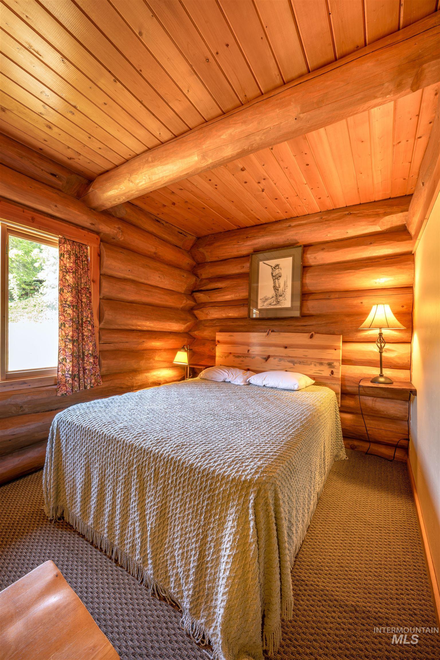 Bedroom with wooden ceiling and log walls
