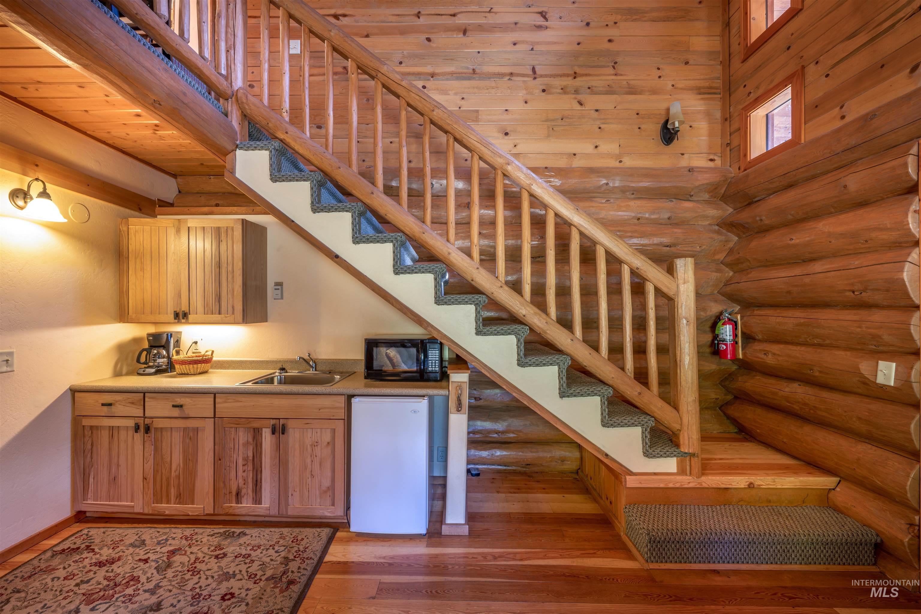 Stairs featuring log walls and wood finished floors