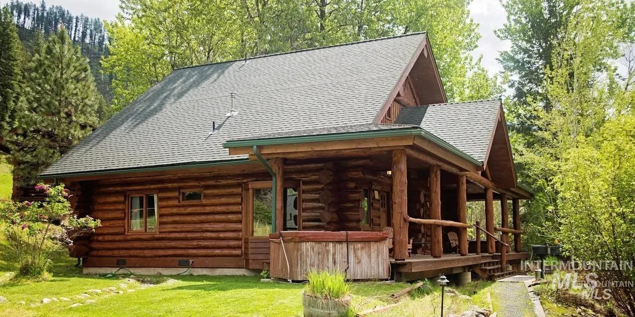 Rear view of house featuring log exterior, roof with shingles, and a lawn