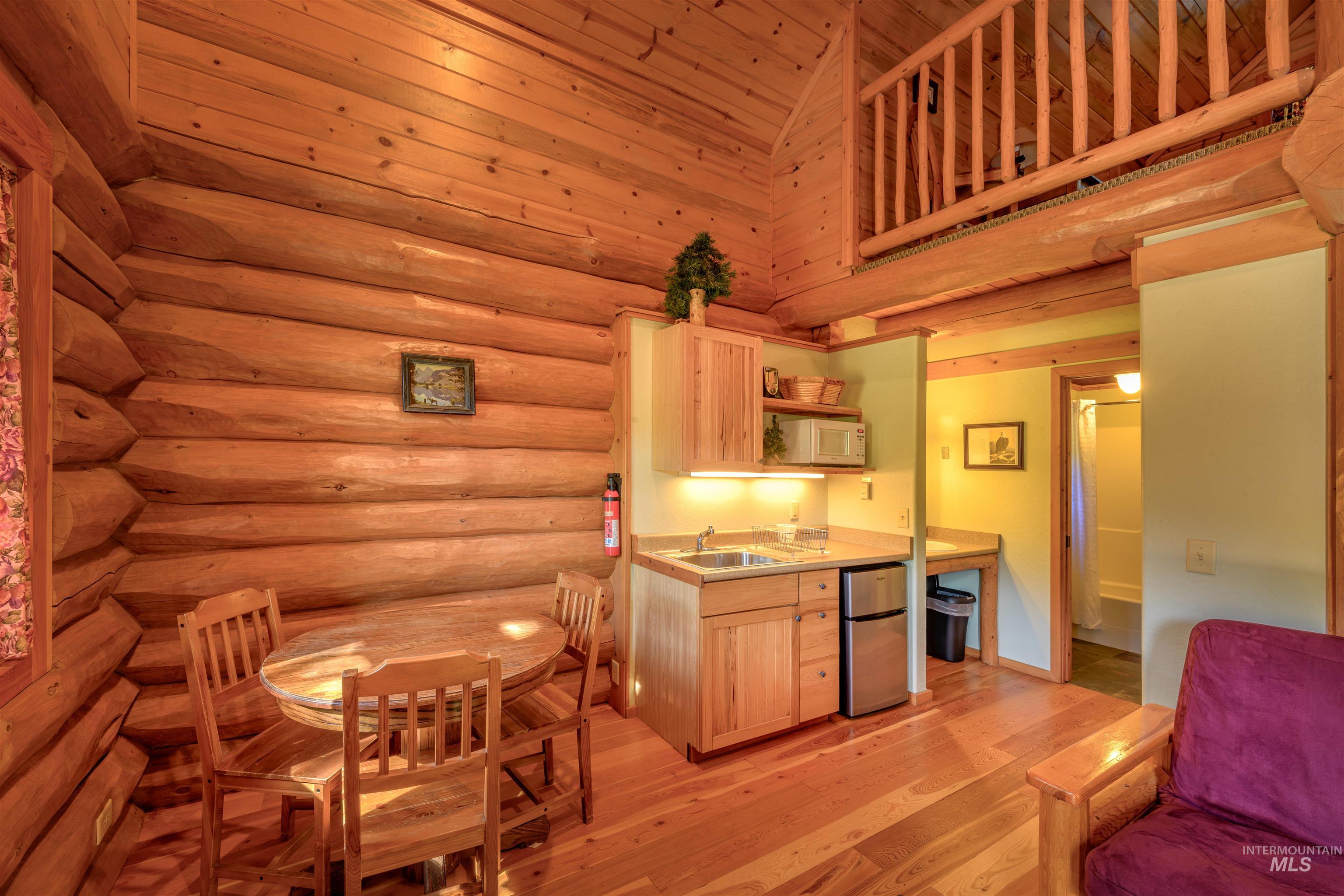 Kitchen with freestanding refrigerator, light brown cabinets, open shelves, white microwave, and light countertops