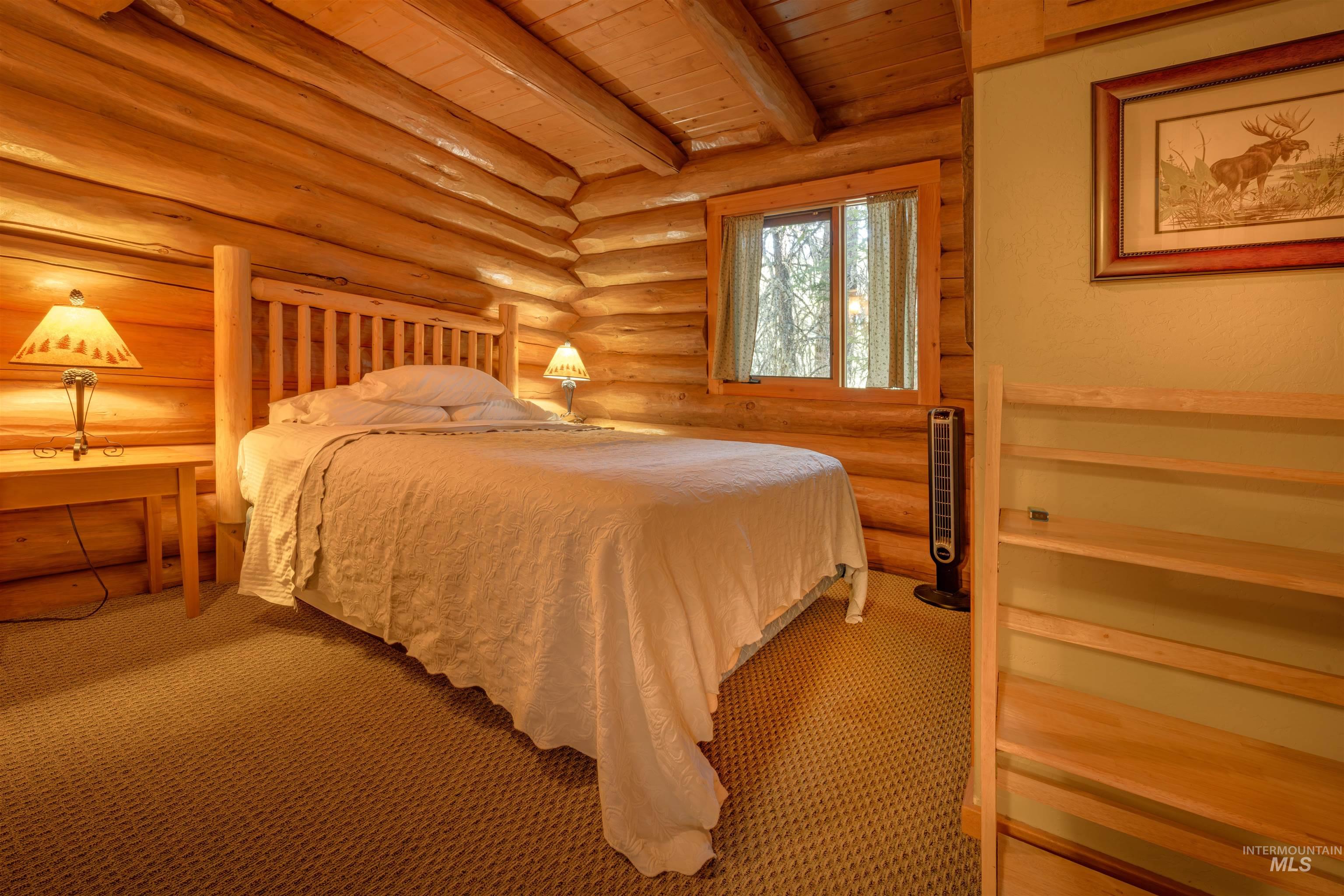 Carpeted bedroom featuring a wood ceiling with exposed beams and log walls