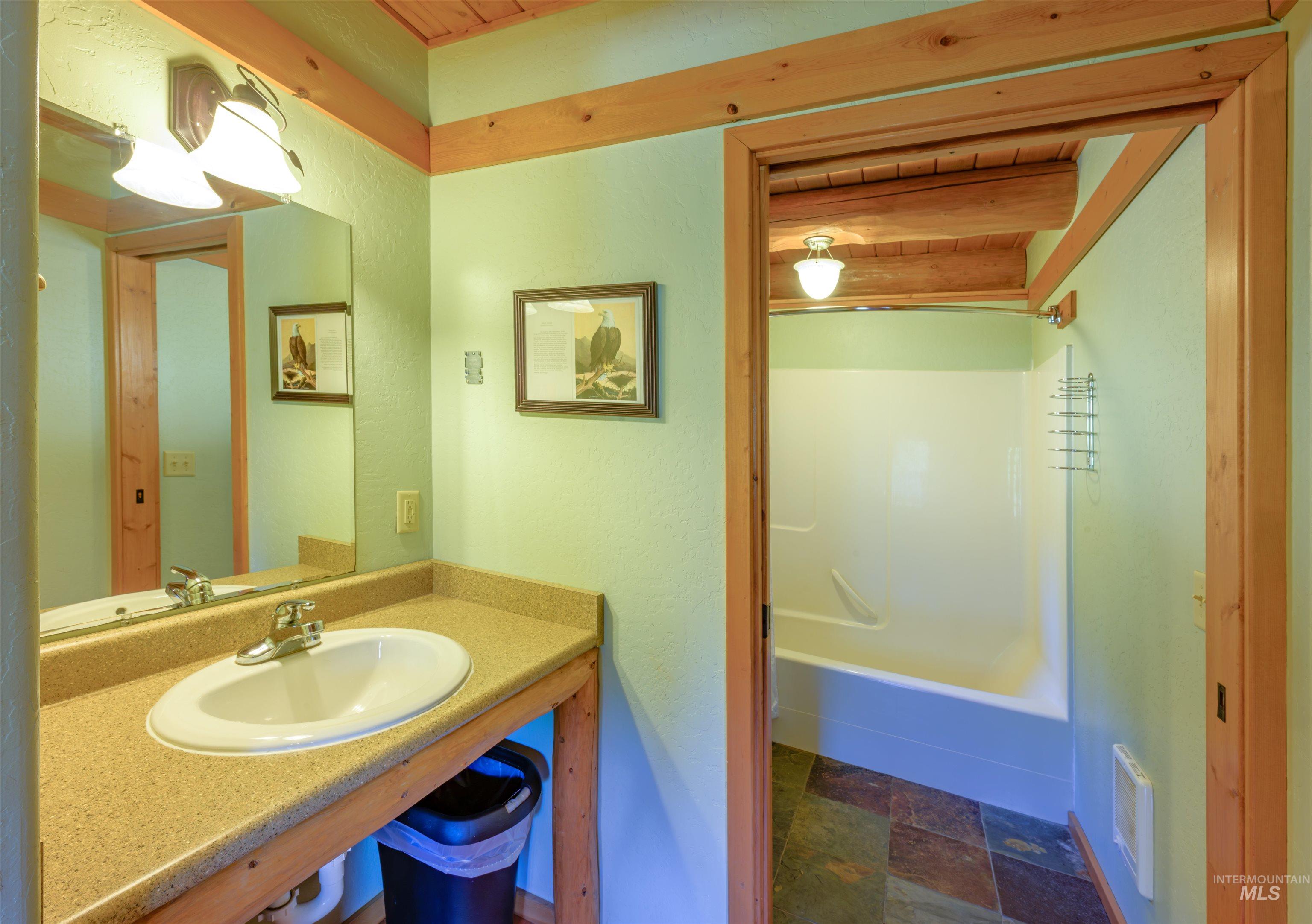 Full bath featuring vanity, stone finish flooring, and  shower combination