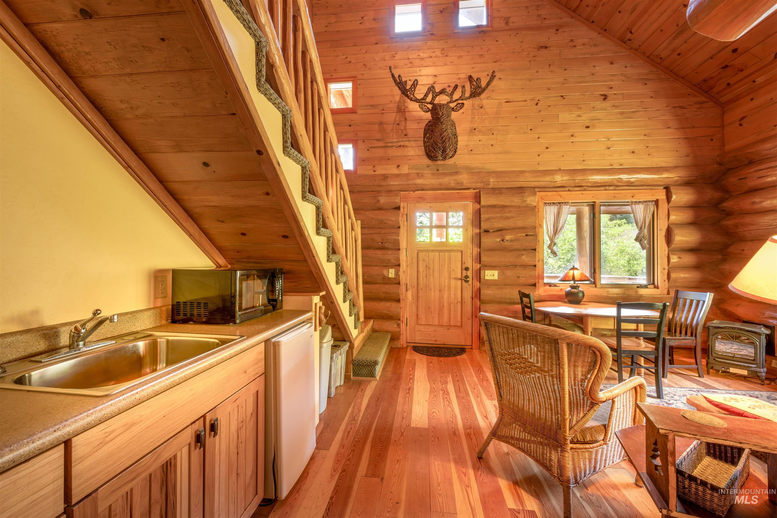 Kitchen featuring black microwave, log walls, wooden ceiling, high vaulted ceiling, and light wood-type flooring