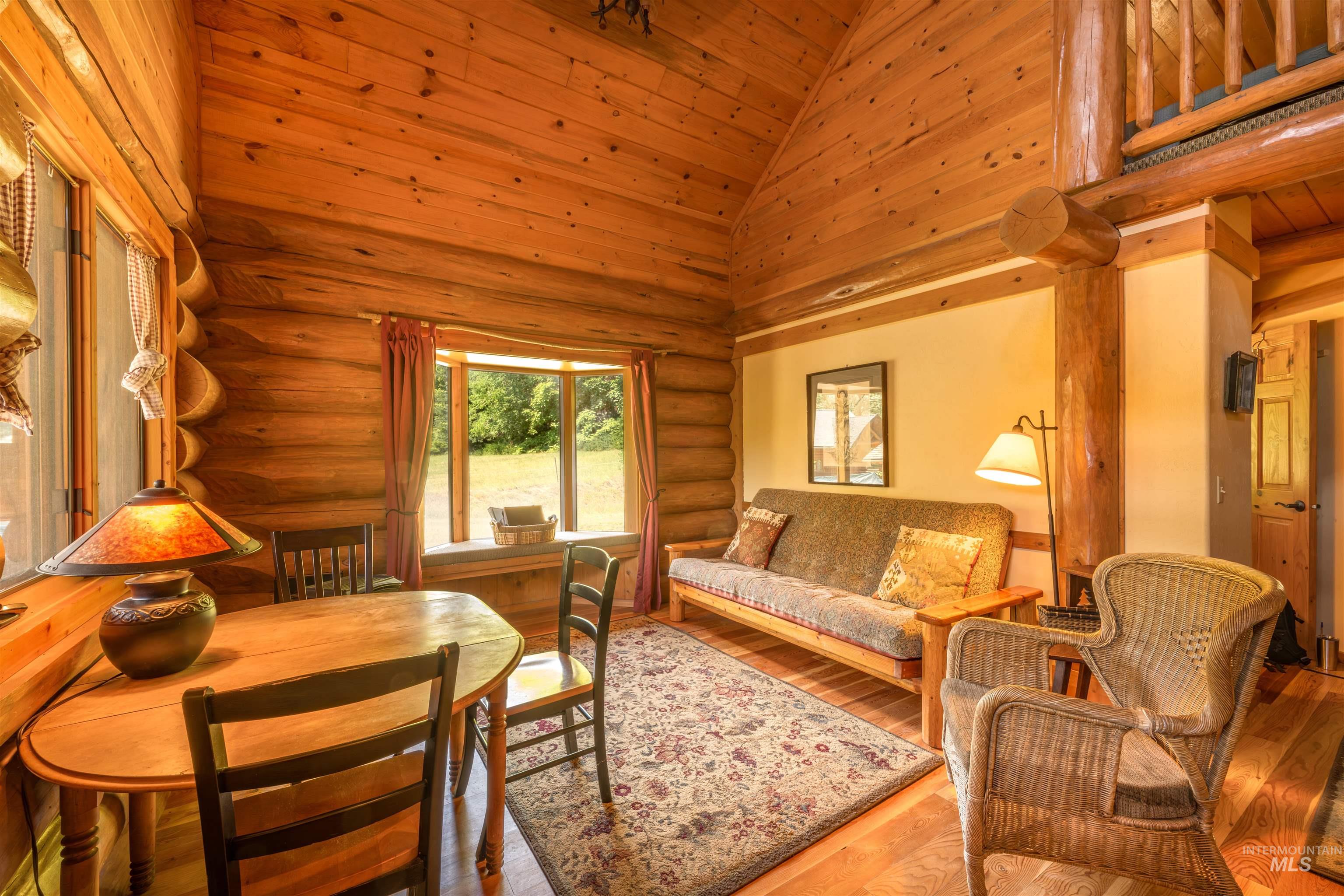 Living room with log walls, high vaulted ceiling, wooden ceiling, and wood finished floors