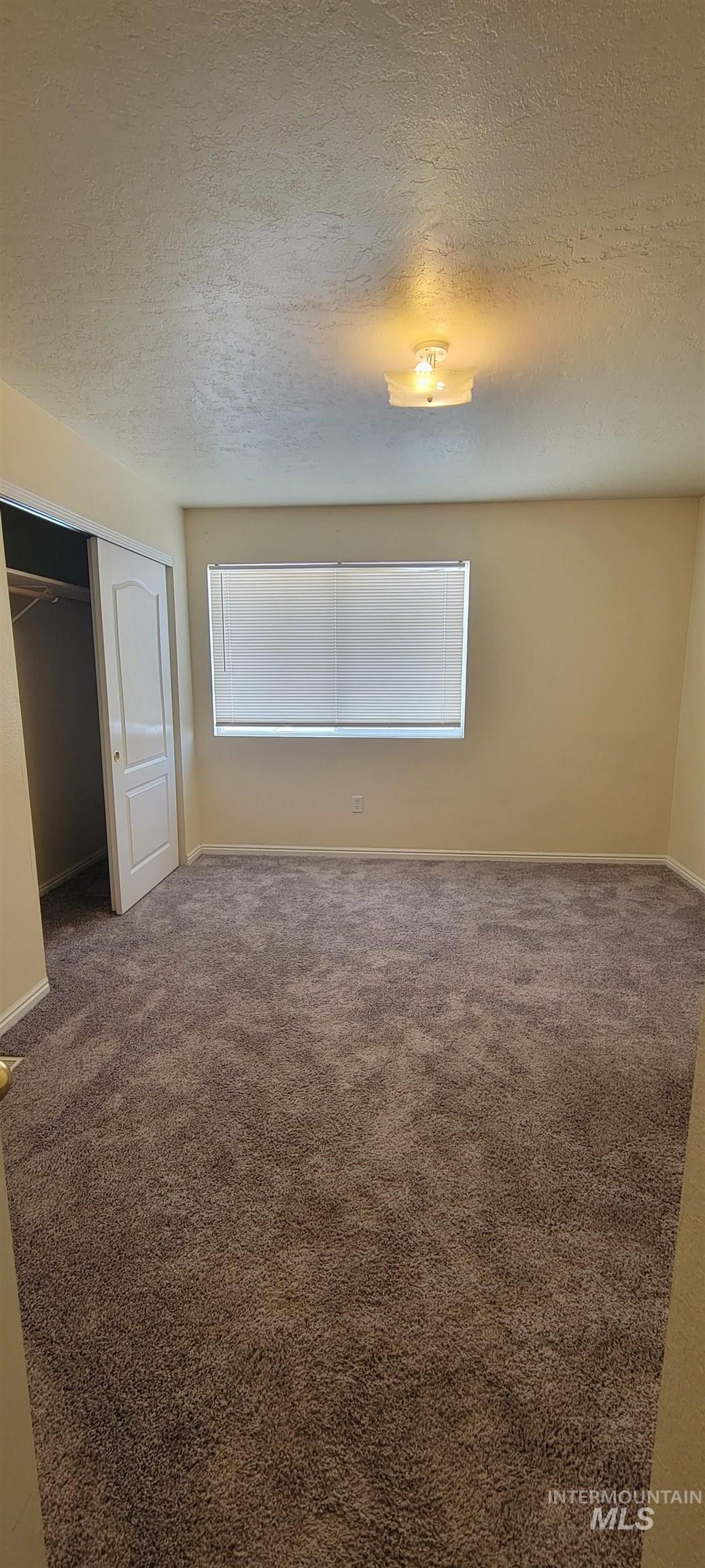 Unfurnished bedroom featuring a textured ceiling, a closet, and carpet floors