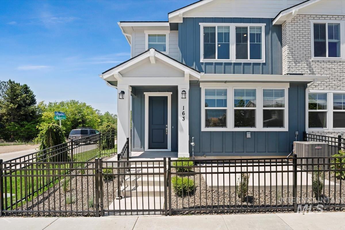View of front of property with board and batten siding, a fenced front yard, and brick siding