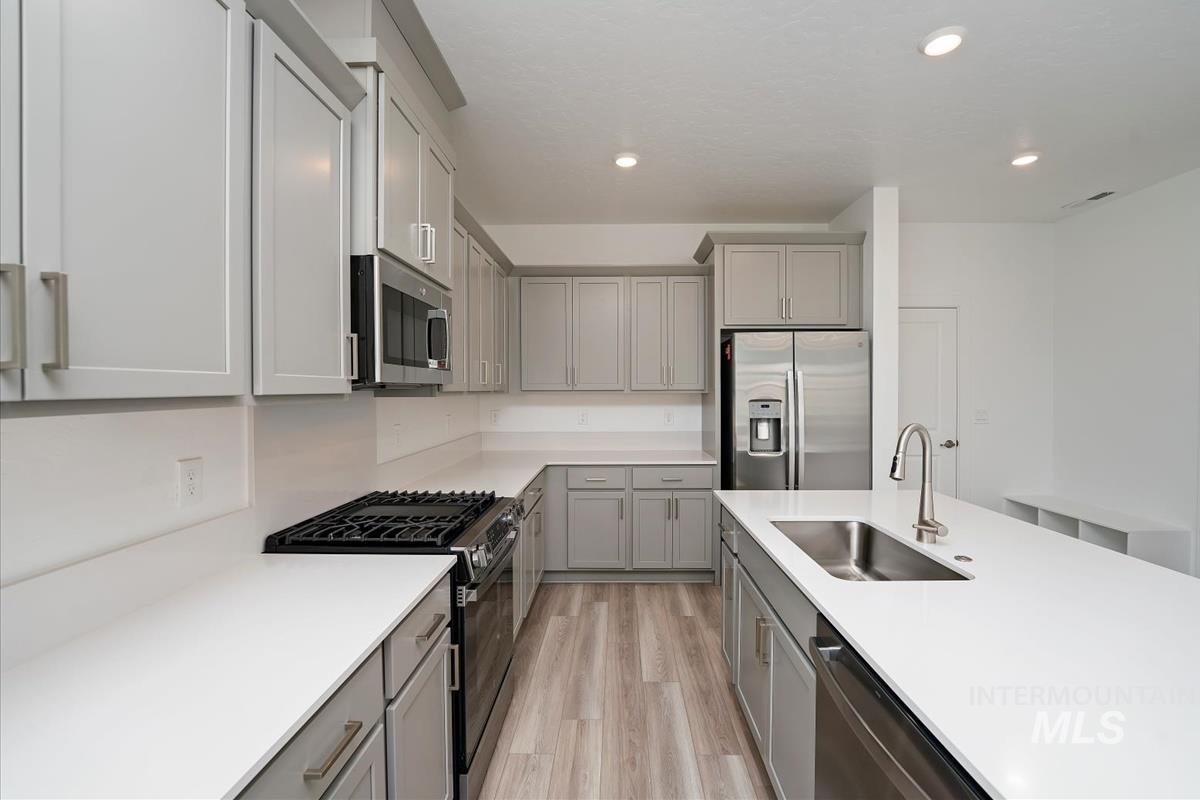 Kitchen featuring gray cabinetry, stainless steel appliances, light wood-style flooring, light countertops, and recessed lighting