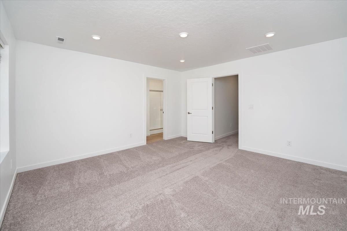 Empty room with light colored carpet, recessed lighting, and a textured ceiling