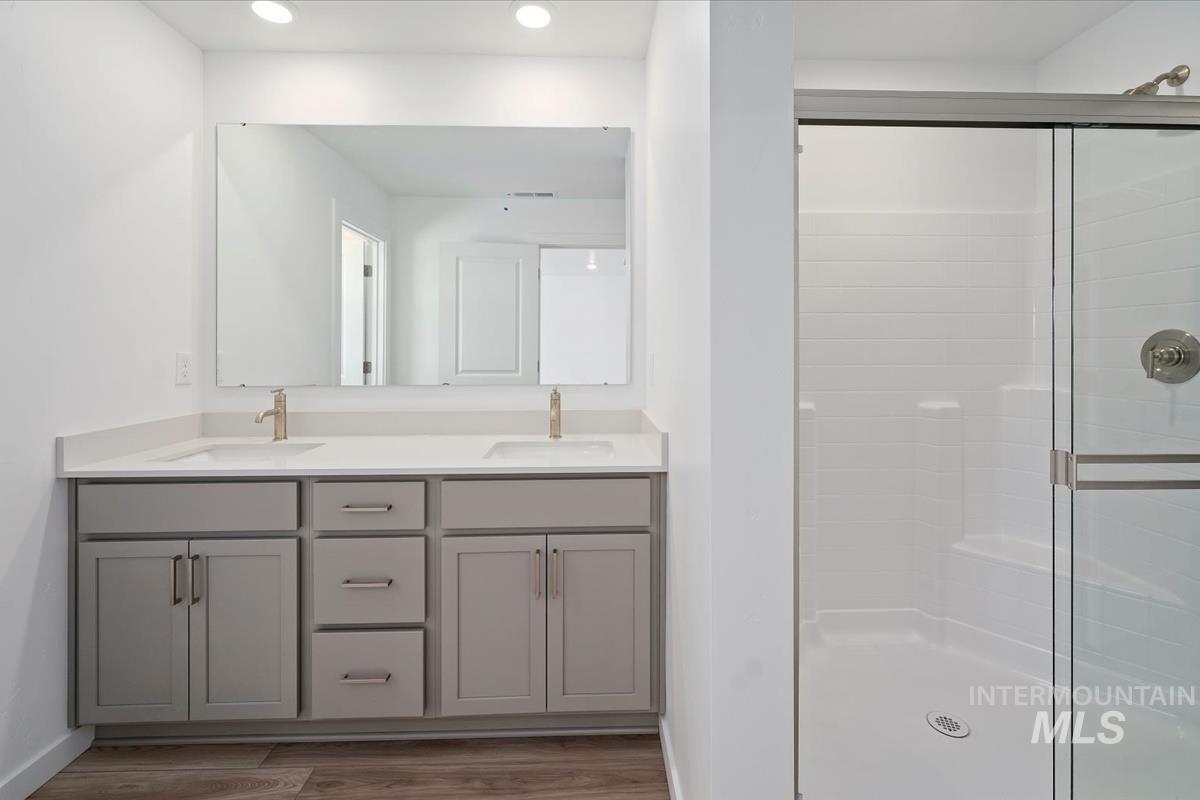 Bathroom with a stall shower, double vanity, and wood finished floors