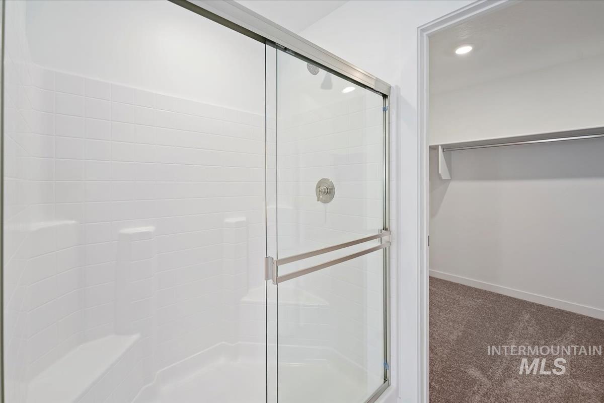 Bathroom featuring a stall shower, a walk in closet, and recessed lighting