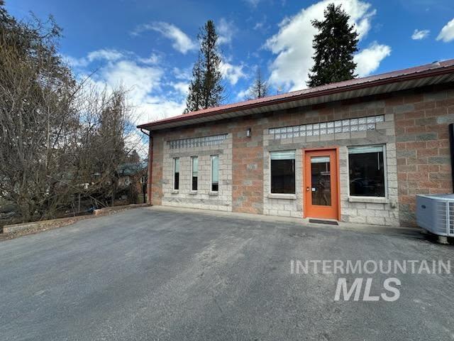 View of side of property featuring stone siding and a metal roof