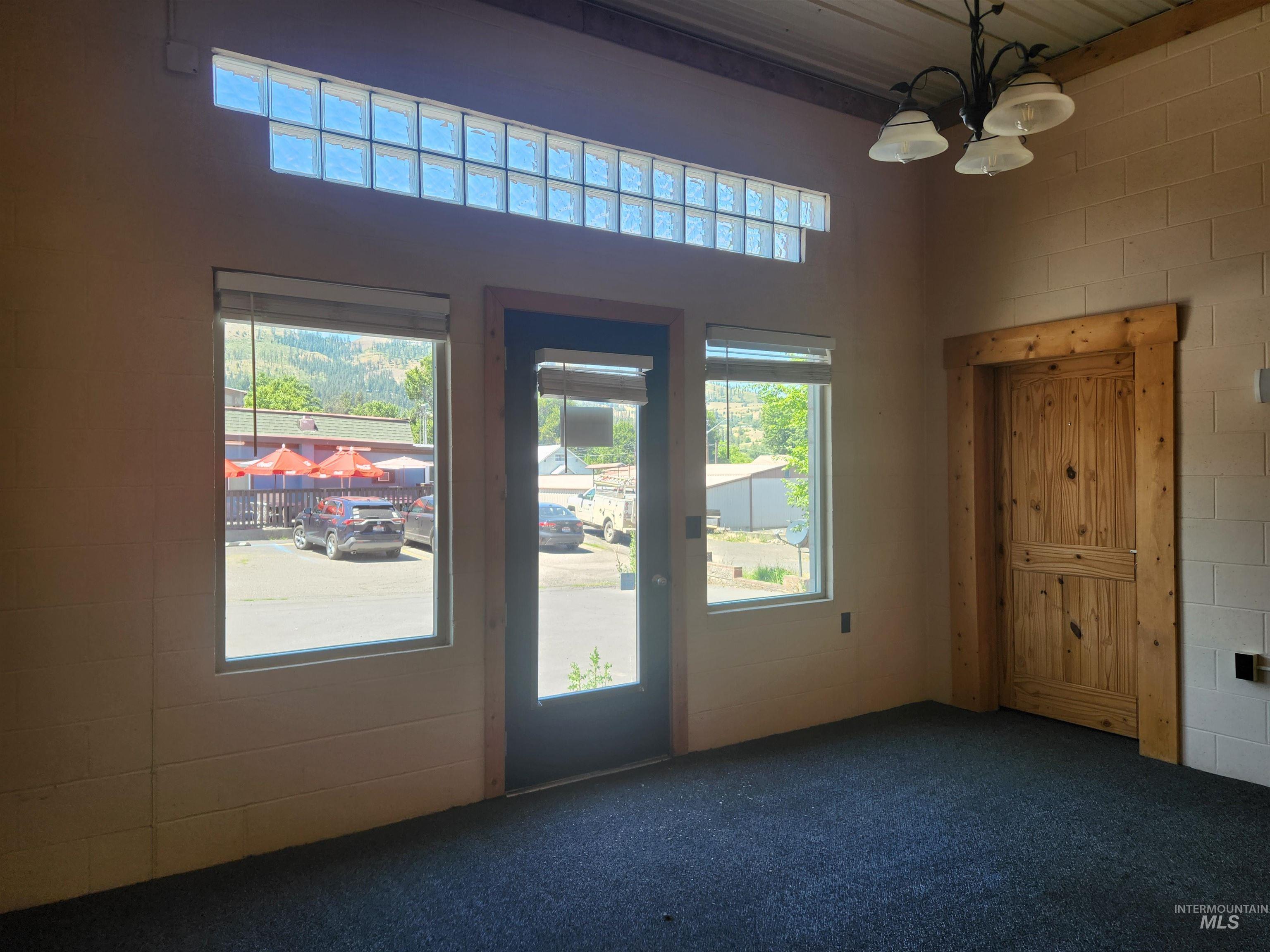 Unfurnished room featuring healthy amount of natural light, carpet flooring, a chandelier, and a high ceiling