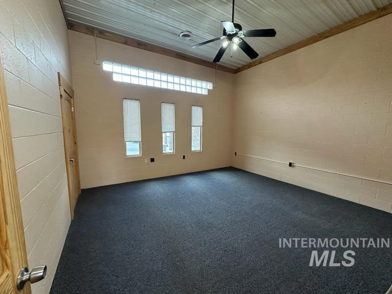 Empty room with ceiling fan and dark carpet