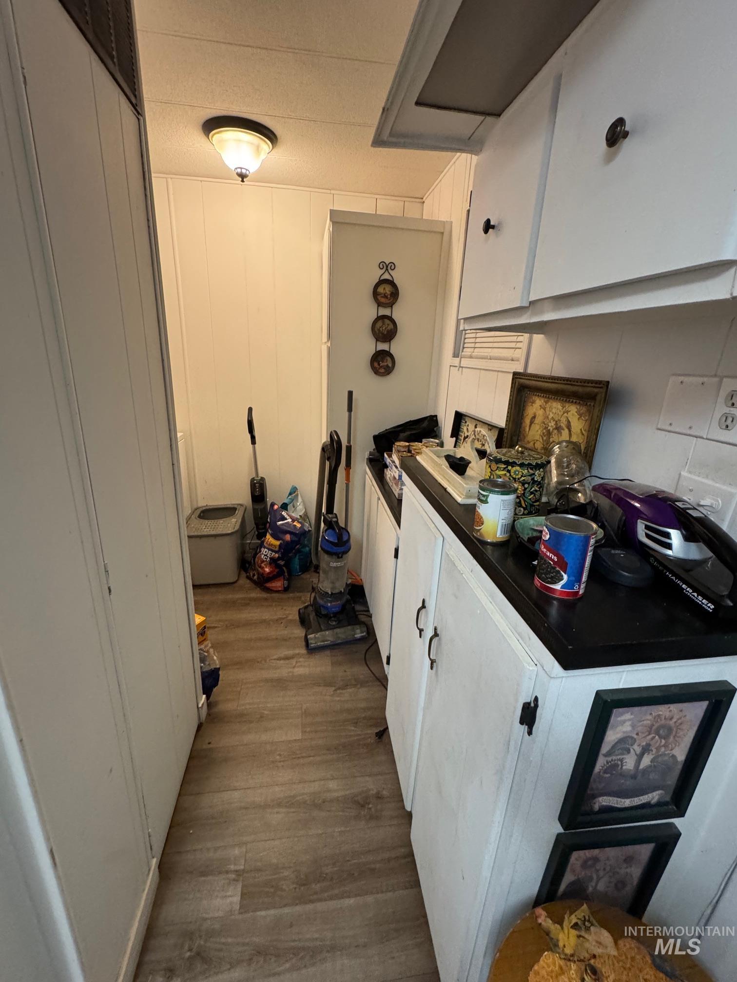 Kitchen featuring dark countertops, wood finished floors, and white cabinetry